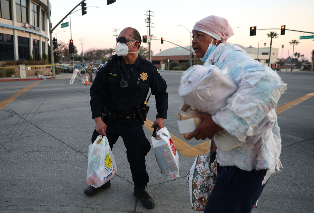 ALTADENA, CALIFORNIA - JANUARY 10: A California Highway Patrol officer assists a resident with her groceries at a checkpoint into the Eaton Fire evacuation area on January 10, 2025 in Altadena, California. Fueled by intense Santa Ana Winds, the Eaton Fire has grown to over 13,000 acres and has destroyed over 5,000 homes and businesses. Five people have lost their lives in the fire. 