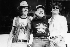 Neil Young, Willie Nelson, and John Mellencamp stand together on stage during the 1985 Farm Aid.